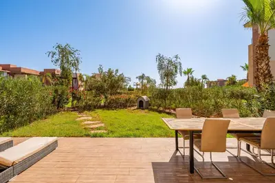 a patio with a table and chairs and a yard at Prestigia Agate Appartement luxueux Marrakech golf city in Marrakech