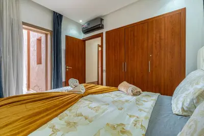 a bedroom with a large bed with a yellow blanket at Prestigia Agate Appartement luxueux Marrakech golf city in Marrakech
