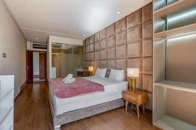 a bedroom with a large bed and a wooden floor at Prestigia Agate Appartement luxueux Marrakech golf city in Marrakech