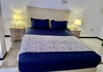 a bedroom with a large bed with blue sheets and two lamps at Appart zénith in Marrakech