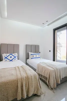 two beds in a bedroom with white walls and a window at The Right Address - Hivernage Marrakech in Marrakech