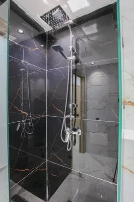 a bathroom with a shower with black marble walls at The Right Address - Hivernage Marrakech in Marrakech