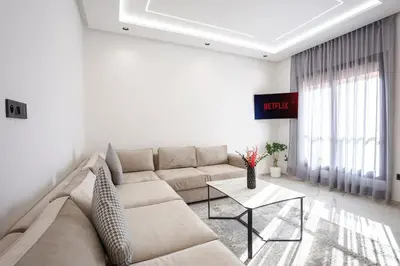 a white living room with a couch and a table at The Cozy Corner - Hivernage Marrakech in Marrakech