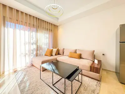 a living room with a couch and a glass table at Appartement KENZ Nouria avec piscine in Marrakech