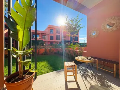 a room with a plant and a chair and a window at Appartement KENZ Nouria avec piscine in Marrakech