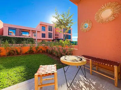 a patio with a table and chairs and a building at Appartement KENZ Nouria avec piscine in Marrakech
