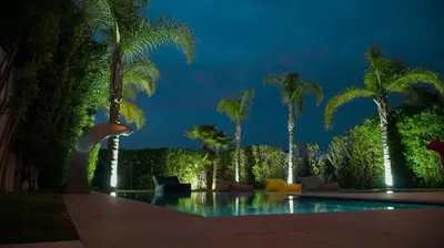 a swimming pool with palm trees at night at villa argana golf in Marrakech