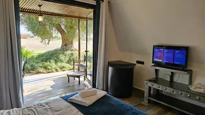 a bedroom with a bed and a television and a sliding glass door at Oasis Of peace Chalet A-frame Atlas view in Aït Amara