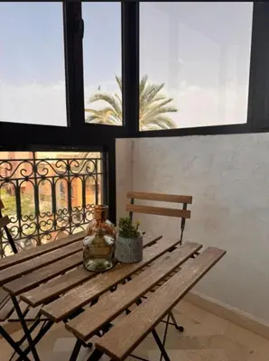 a wooden bench sitting in front of a window at Résidence Caricia - WiFi, Piscine, Parking, Gardien h24 in Marrakech