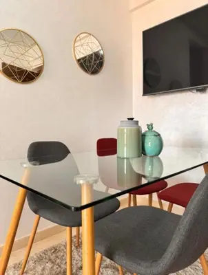 a dining room with a glass table and chairs at Résidence Caricia - WiFi, Piscine, Parking, Gardien h24 in Marrakech
