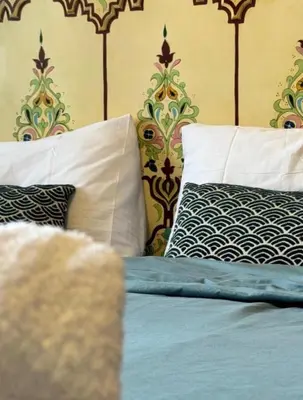 a bed with blue sheets and pillows in a bedroom at Résidence Caricia - WiFi, Piscine, Parking, Gardien h24 in Marrakech