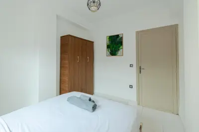 a bedroom with a white bed and a wooden cabinet at Modern studio with terrace in Marrakech