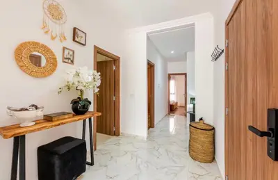 a hallway with white walls and a table with flowers on it at Premium Holliday Marrakesh in Marrakech