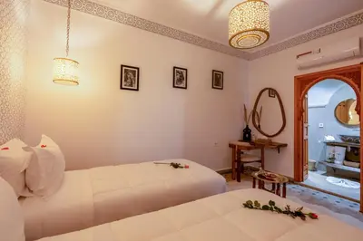 a bedroom with two white beds and a mirror at Riad Secret De Medina in Marrakech