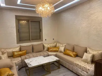 a living room with a couch and a chandelier at Apparemment cosy pour famille in Marrakech