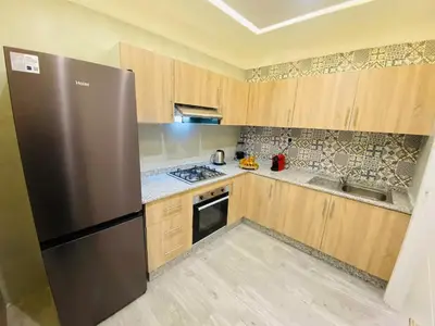 a kitchen with a stainless steel refrigerator and wooden cabinets at Apparemment cosy pour famille in Marrakech