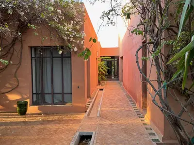 an alleyway between two orange buildings with flowers at Villa DarJ in Marrakech