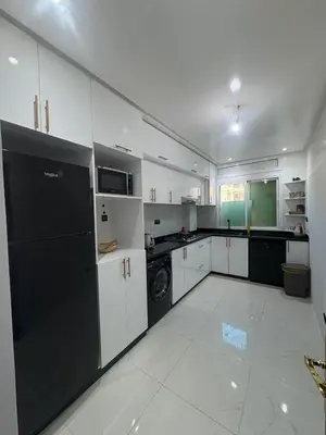 a kitchen with white cabinets and a black refrigerator at Prestige Gueliz city centre appartement in Marrakech
