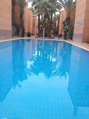 a large blue swimming pool in a building at Riad authentique dans une résidence sécurisée in Marrakech