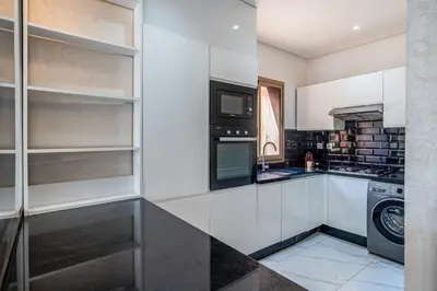 a kitchen with white cabinets and a washer and dryer at Sunny Getaway with Pool Access & Private Yard in Marrakech