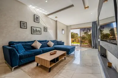 a living room with a blue couch and a table at Sunny Getaway with Pool Access & Private Yard in Marrakech