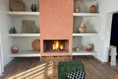 a fireplace in a living room with logs and shelves at Villa Léa 2 Marrakech in Marrakech