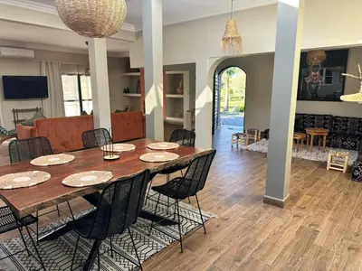 a dining room and living room with a table and chairs at Villa Léa 2 Marrakech in Marrakech