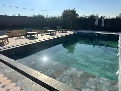 a swimming pool with two chairs and a table at Villa Léa 2 Marrakech in Marrakech