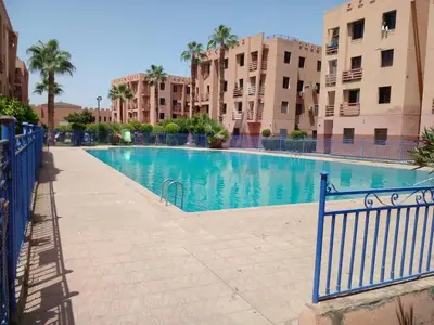 a swimming pool in a building with palm trees and buildings at Casa Rosa in Marrakech