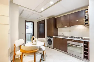 a kitchen with wooden cabinets and a table and chairs at Suite Moderne Deluxe Miracle, à Babylone, Hyper-Centre, Marrakesh in Marrakech