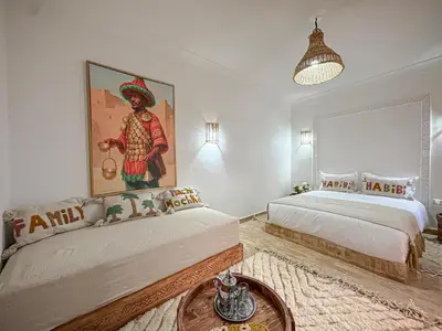 a bedroom with two beds and a painting on the wall at Riad Louzaia, Marrakech in Marrakech