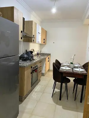 a kitchen with a table with chairs and a refrigerator at Appartement 2 chambres à Gueliz avec piscine Emplacement parfait in Marrakech