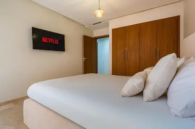 a white bed with pillows in a bedroom at Gueliz apartment with pool, spa and gym in Marrakech
