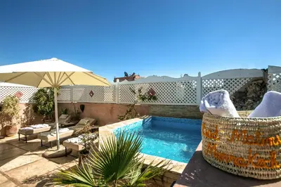 a patio with a swimming pool and an umbrella at Riad Matins De Marrakech in Marrakech
