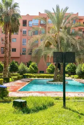 a swimming pool in front of a building with palm trees at Stylish Magnifique Duplex de Standing, 3 Chambres, Piscine, Proche de Gueliz in Marrakech