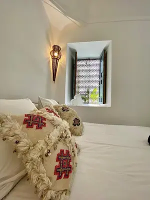 a white bed with two pillows and a window at Riad 191 - Maison privée, spa & piscine in Marrakech