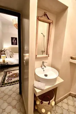 a bathroom with a sink and a mirror and a bed at Riad 191 - Maison privée, spa & piscine in Marrakech