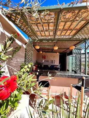 an outdoor patio with a pergola and a red flower at Riad 191 - Maison privée, spa & piscine in Marrakech