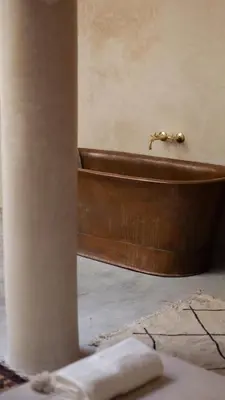 a brown bath tub in a room with a pillar at Dar Alma Modernist Designer Riad with Pool in Marrakech