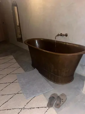a copper bath tub with a pair of shoes on the floor at Dar Alma Modernist Designer Riad with Pool in Marrakech