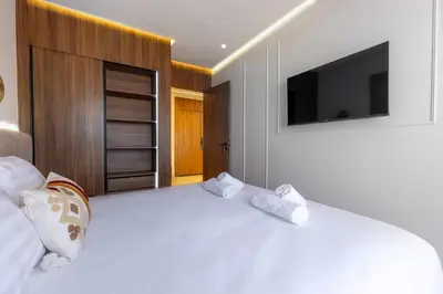 a bedroom with a large white bed with a flat screen tv at grand studio hypercentre de marrakech et proche gare in Marrakech