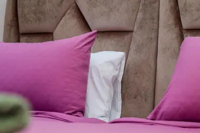 a bed with pink and white pillows on it at Oasis Urban avec Balcon - 5min de l'aéroport in Marrakech
