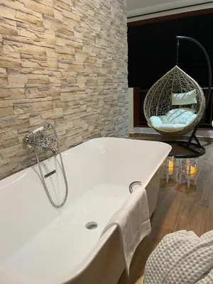 a bath tub in a bathroom with a stone wall at Appartement moderne terrasse avec baignoire privée in Marrakech