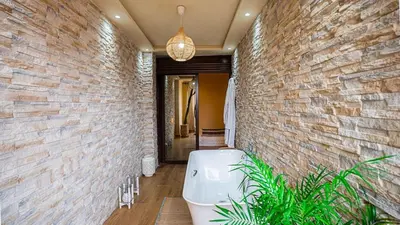 a bathroom with a bath tub in a brick wall at Appartement moderne terrasse avec baignoire privée in Marrakech