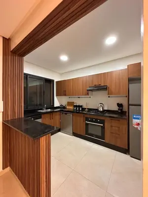 a large kitchen with wooden cabinets and black counter tops at Appartement luxueux avec piscine in Marrakech