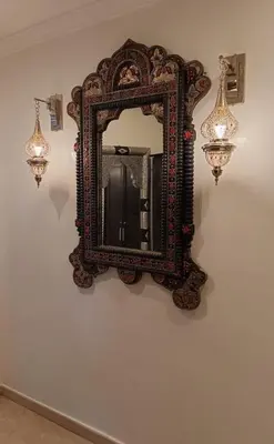 an ornate mirror on a wall with two lights at Kasbah Bastoff in Marrakech