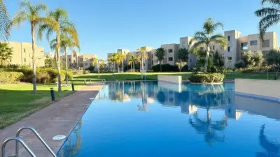 a large swimming pool with palm trees and buildings at La Perle de Marrakech in Marrakech