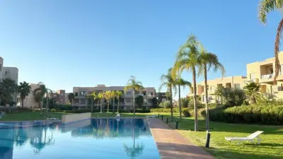 a swimming pool with palm trees and buildings at La Perle de Marrakech in Marrakech