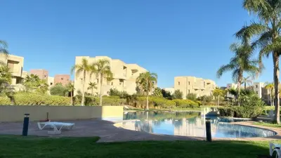 a resort with a pool and palm trees and buildings at La Perle de Marrakech in Marrakech