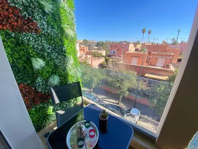 a room with a table and a window with a green wall at Small Cosy & Balcon & Vue Palmier et Montagne in Marrakech